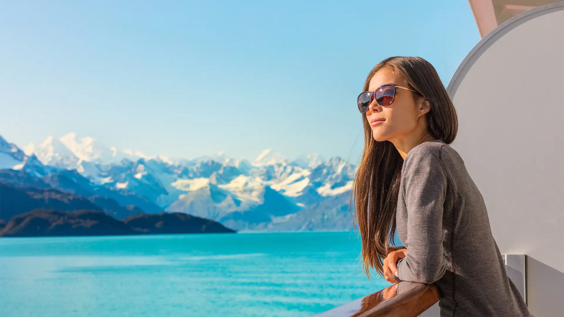 A Woman looking out over the balcony of a cruise ship at Alaska