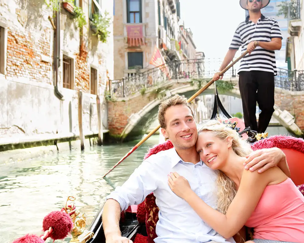 A couple on a gondola ride down a Venice canal