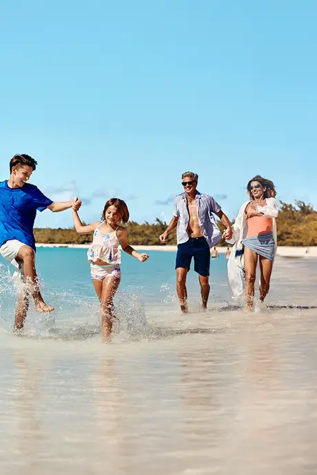 A Family running down Half Moon Beach on Half Moon Cay