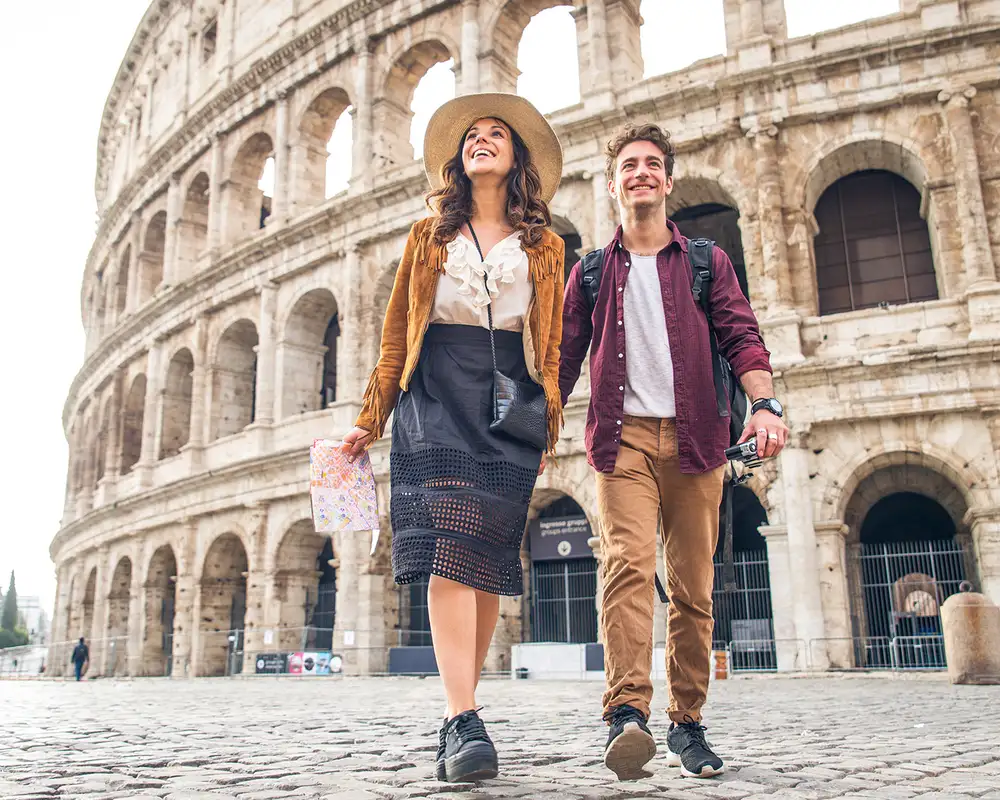 A couple walking infront of the Roman Colosseum