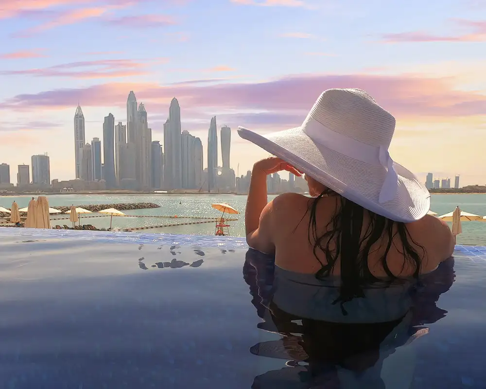 A woman looking out over the skyline of Dubai from a pool