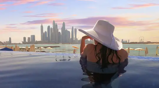 A woman looking out over the skyline of Dubai from a pool