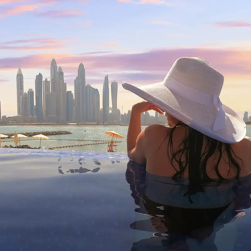 A woman looking out over the skyline of Dubai from a pool
