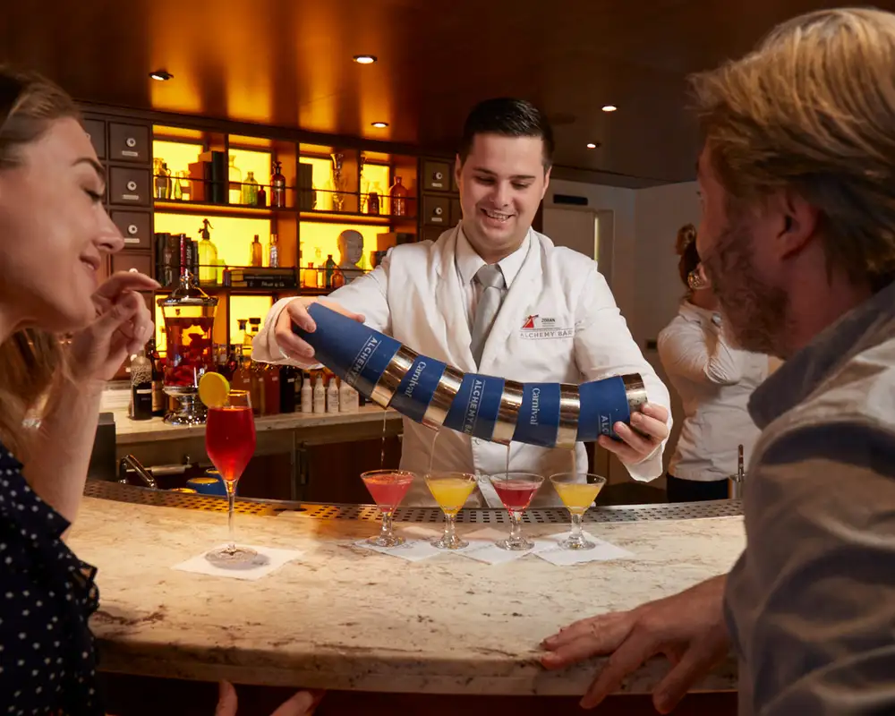 A couple watching a bartender make martinis aboard a Carnival Cruise Ship