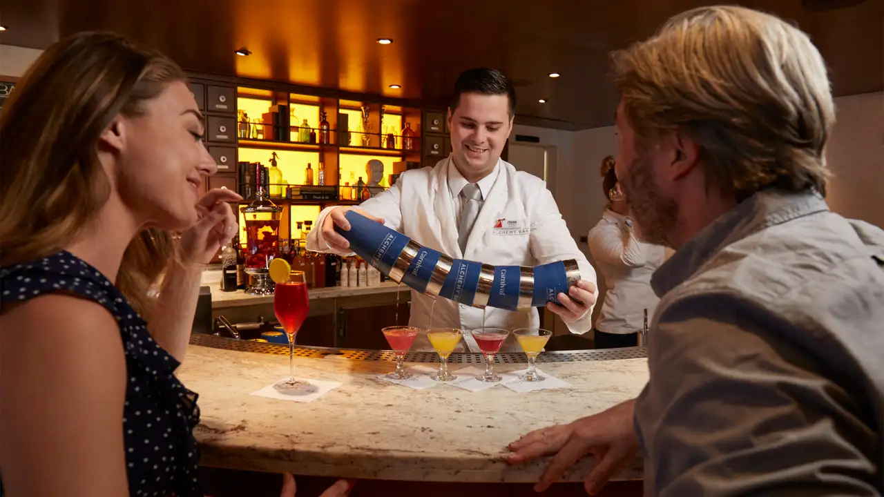 A couple watching a bartender make martinis aboard a Carnival Cruise Ship
