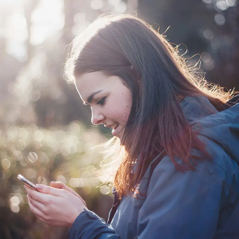 A Woman using a phone in a forest