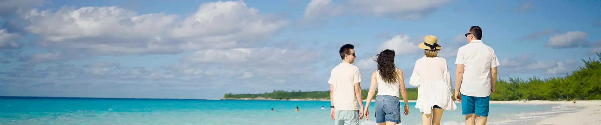 A family walking down the shore of a beach on Half Moon Cay