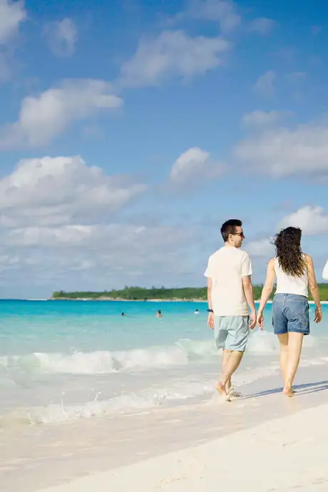 A family walking down the shore of a beach on Half Moon Cay