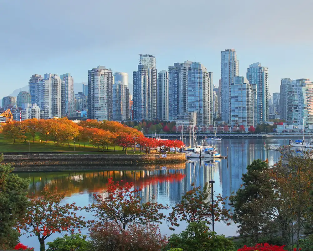 A view of the Vancouver skyline behind a river and a park