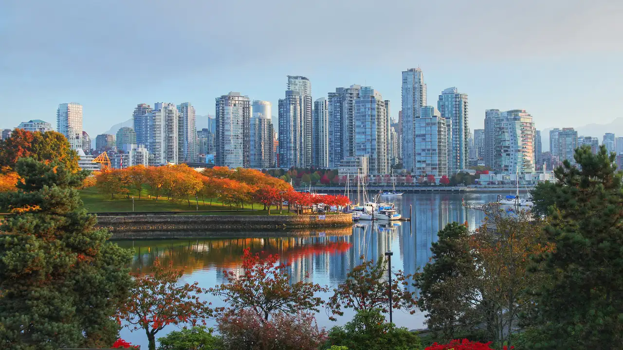 A view of the Vancouver skyline behind a river and a park