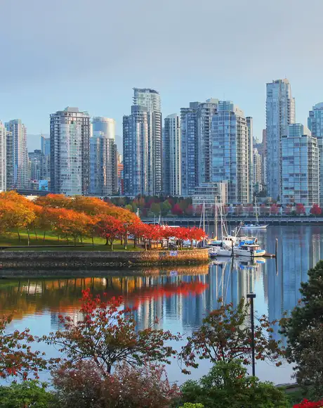 A view of the Vancouver skyline behind a river and a park