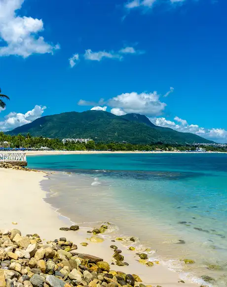 A Caribbean beach with a mountain in the distance