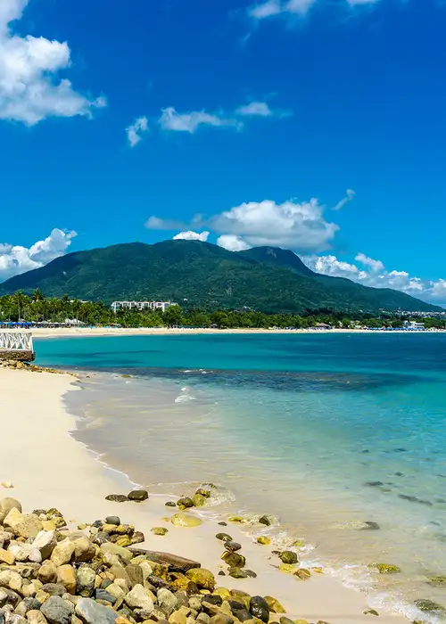 A Caribbean beach with a mountain in the distance