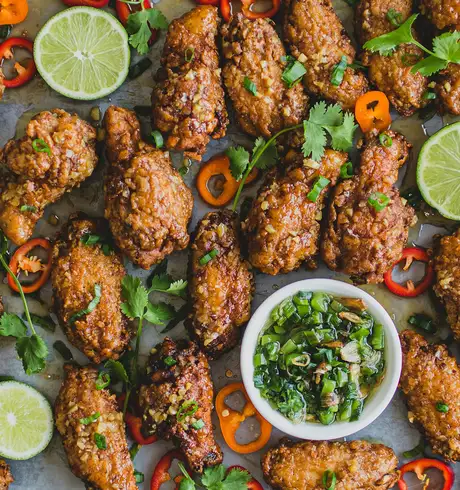 A Tray of fried chicken, chillies and limes