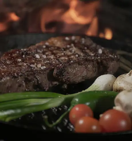 A steak and vegetables cooking on a grill