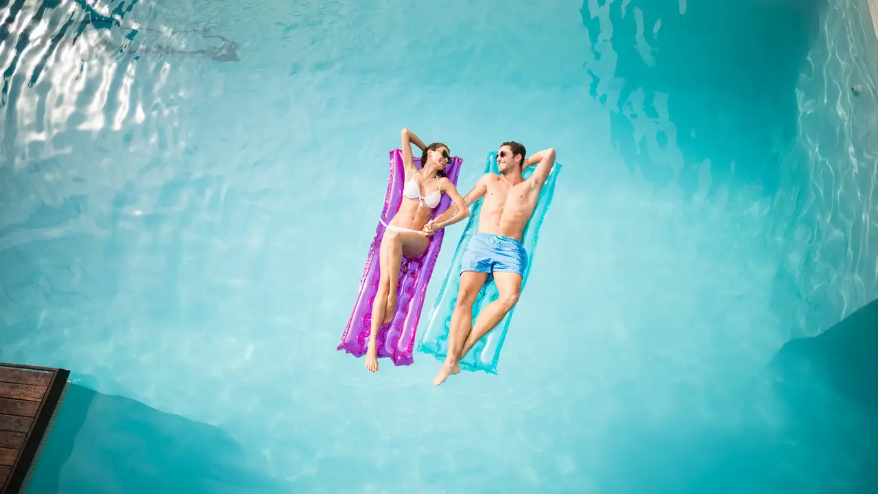 A couple on relaxing on floats in a pool