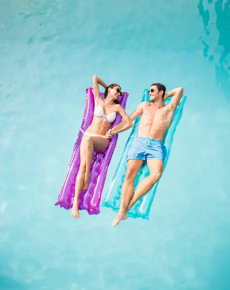 A couple on relaxing on floats in a pool