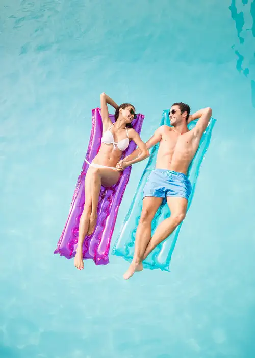 A couple on relaxing on floats in a pool