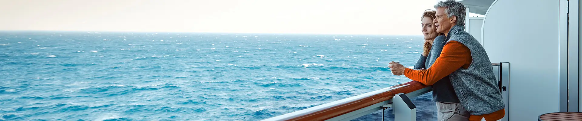 A couple leaning on a railing on a Holland America Ship