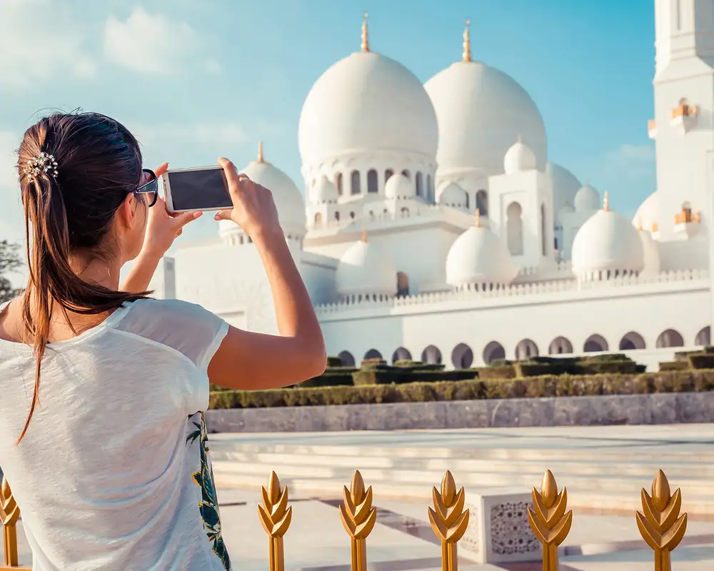 A woman taking a picture of a White Temple in Dubai with her phone