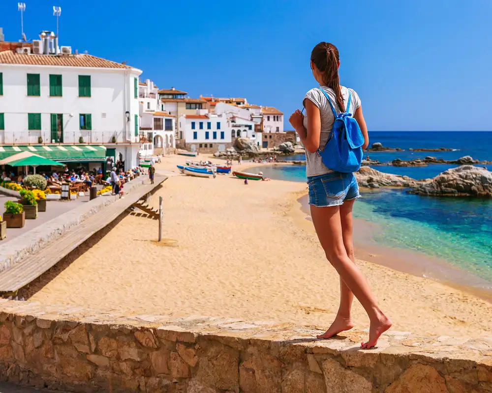 A woman walking along a wall next to a beach in Barcelona, Spain