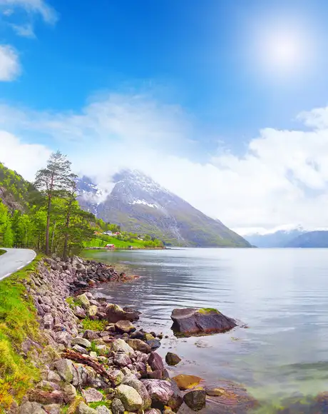 An image of Eidfjord, showing a footpath next to the fjord with mountains in the distance