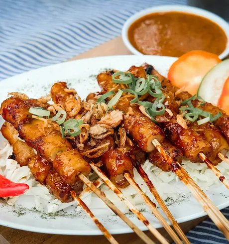 Meat skewers over rice with some chillies and other vegetables