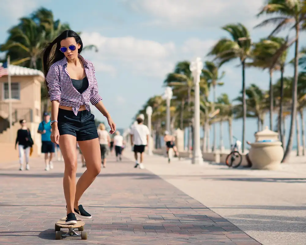 A Woman riding a Skateboard down Miami Beach