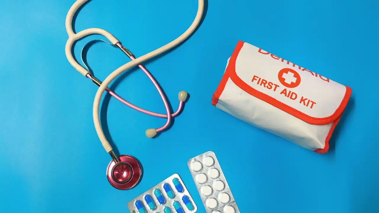 A stethoscope, tablets and a first aid kit on a blue background