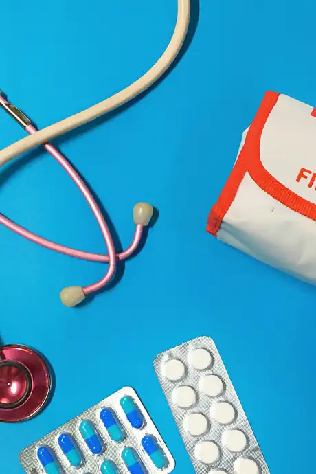 A stethoscope, tablets and a first aid kit on a blue background