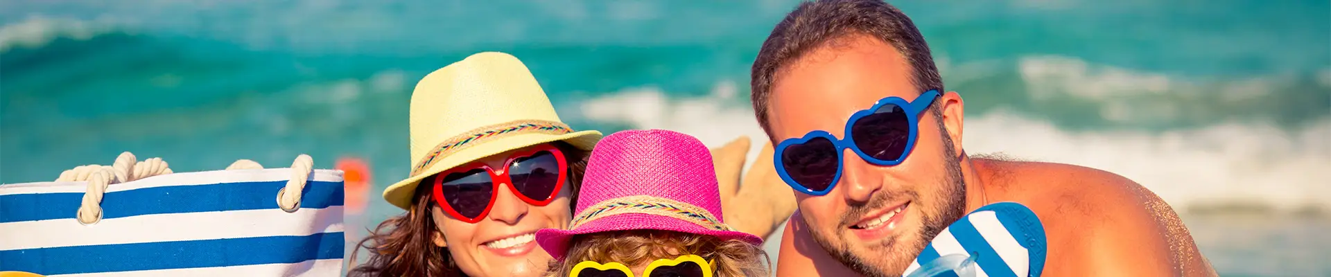 A family at the beach, looking at the camera with matching sunglasses