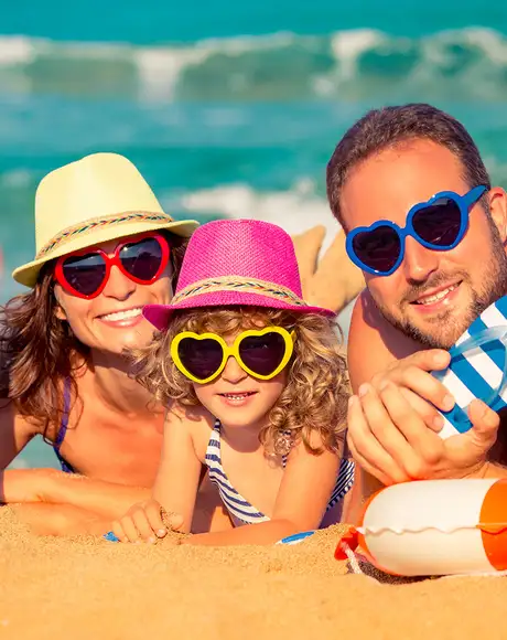 A family at the beach, looking at the camera with matching sunglasses