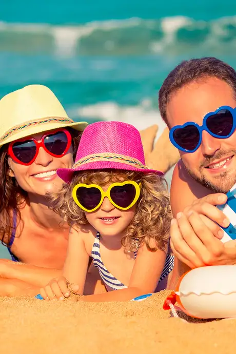 A family at the beach, looking at the camera with matching sunglasses