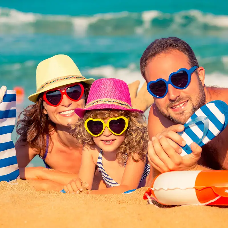 A family at the beach, looking at the camera with matching sunglasses
