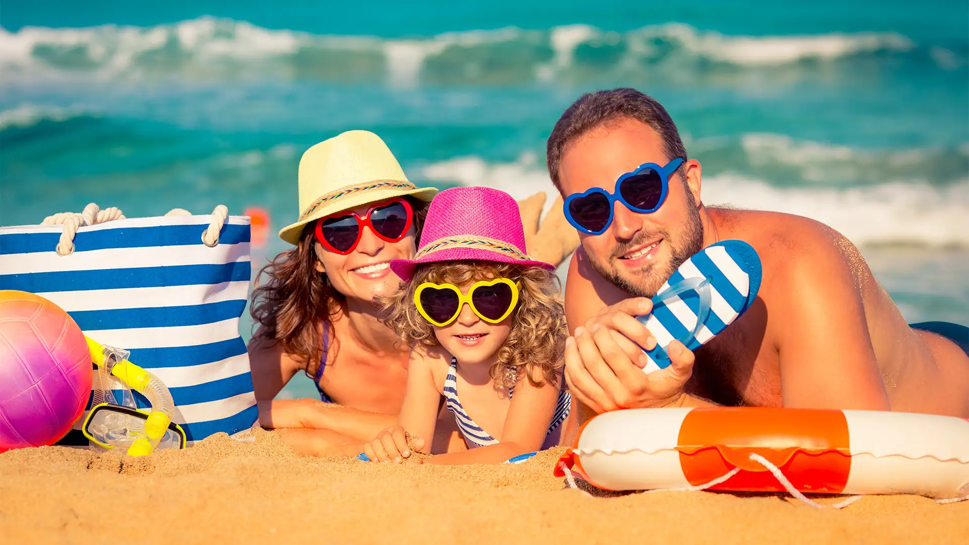 A family at the beach, looking at the camera with matching sunglasses