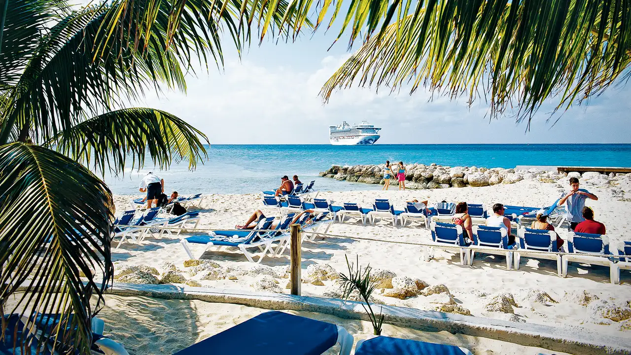 An image of people relaxing on a beach on Princess Cays, with a Princess Cruises ship in the distance