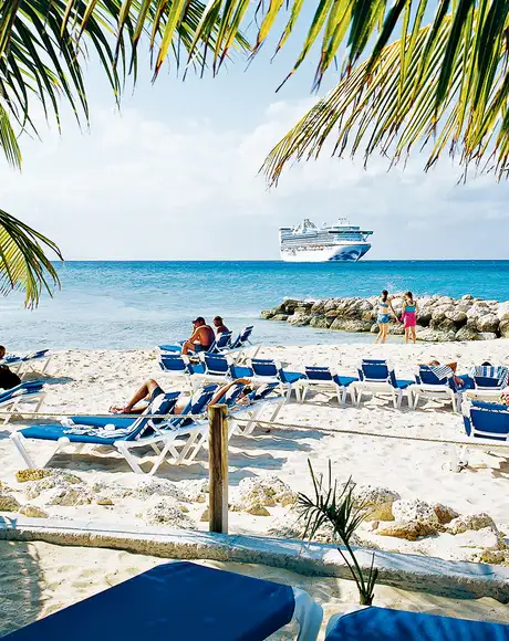 An image of people relaxing on a beach on Princess Cays, with a Princess Cruises ship in the distance