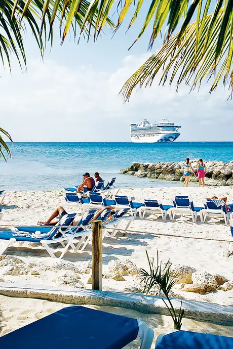 An image of people relaxing on a beach on Princess Cays, with a Princess Cruises ship in the distance