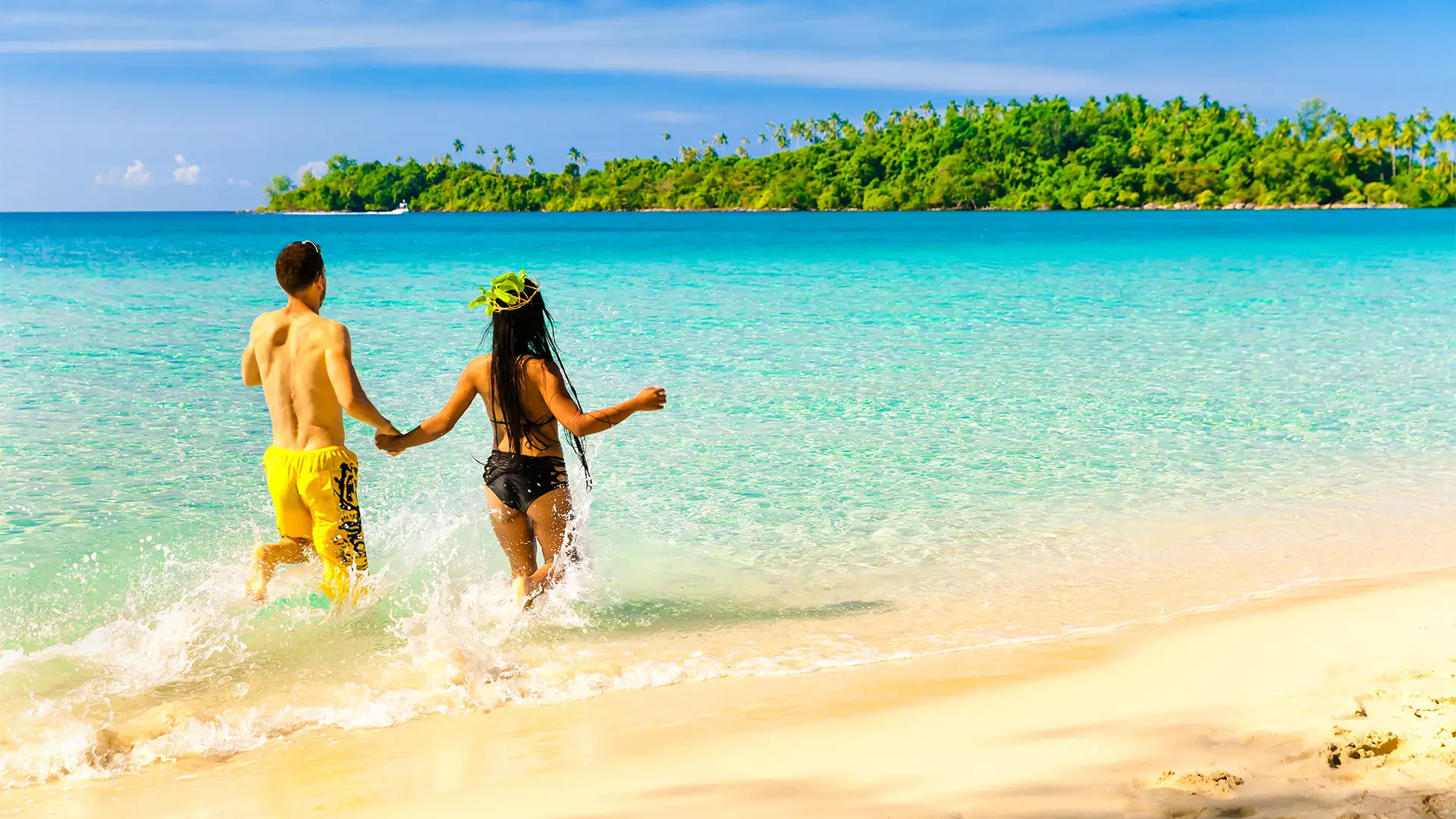 A couple running into the ocean on a caribbean beach