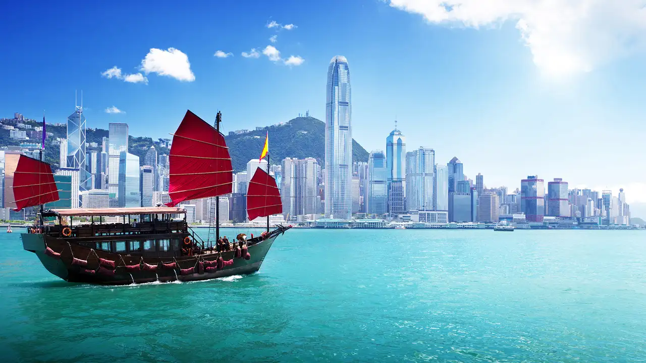 The Skyline of Hong Kong, with a boat sailing across the water in the foreground
