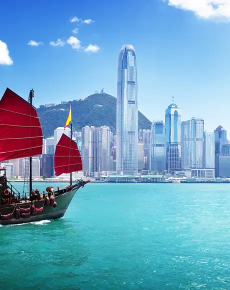 The Skyline of Hong Kong, with a boat sailing across the water in the foreground