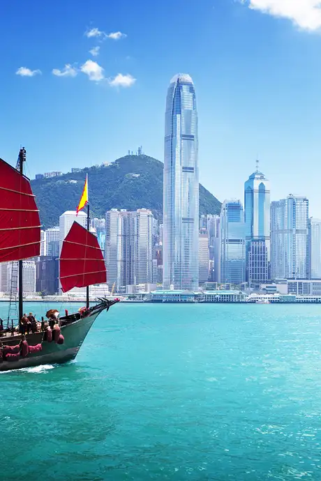 The Skyline of Hong Kong, with a boat sailing across the water in the foreground
