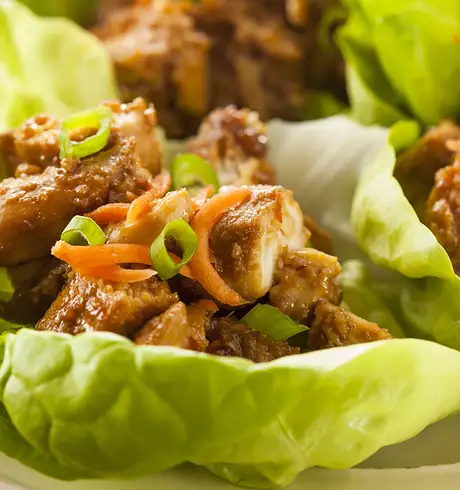 A meal made of chicken sitting in lettuce