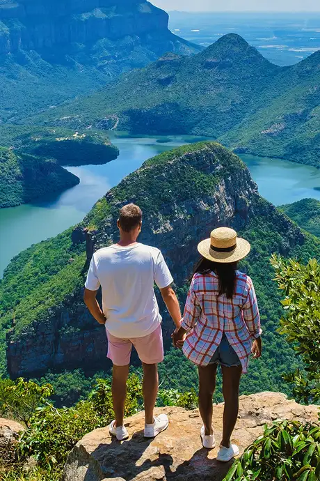 A Couple standing on top of a cliff, looking over the Blyde River Canyon in South Africa
