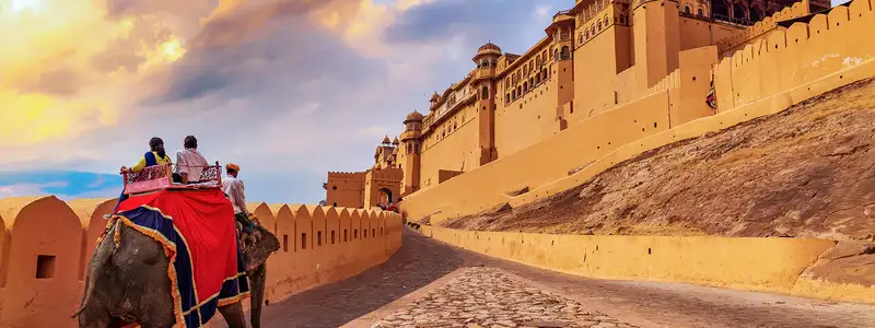 Tourists enjoy an elephant ride at Amer Fort Jaipur Rajasthan at sunset.