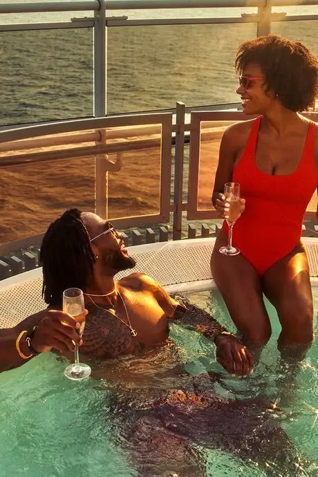 A Couple in a Hot Tub drinking Champagne aboard a Virgin Voyages Ship