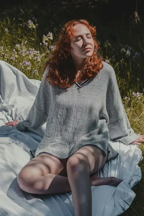 A woman sitting on a white sheet in a field