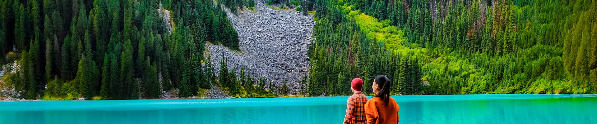 A couple walking on a log looking over Joffre Lake in Canada