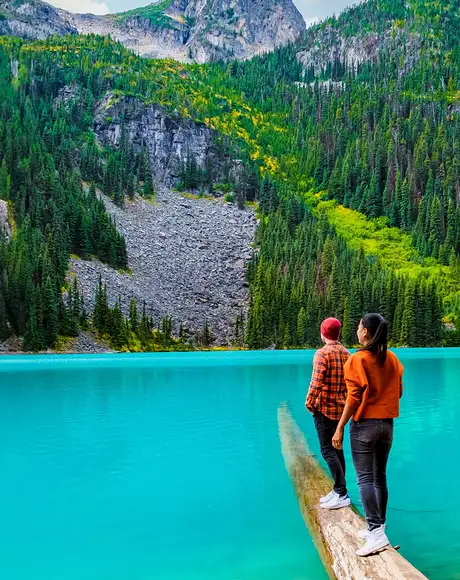 A couple walking on a log looking over Joffre Lake in Canada