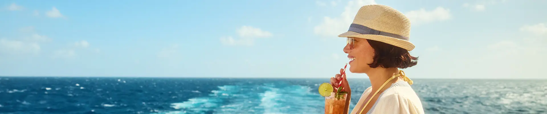 A woman enjoying a drink while looking out at the open ocean